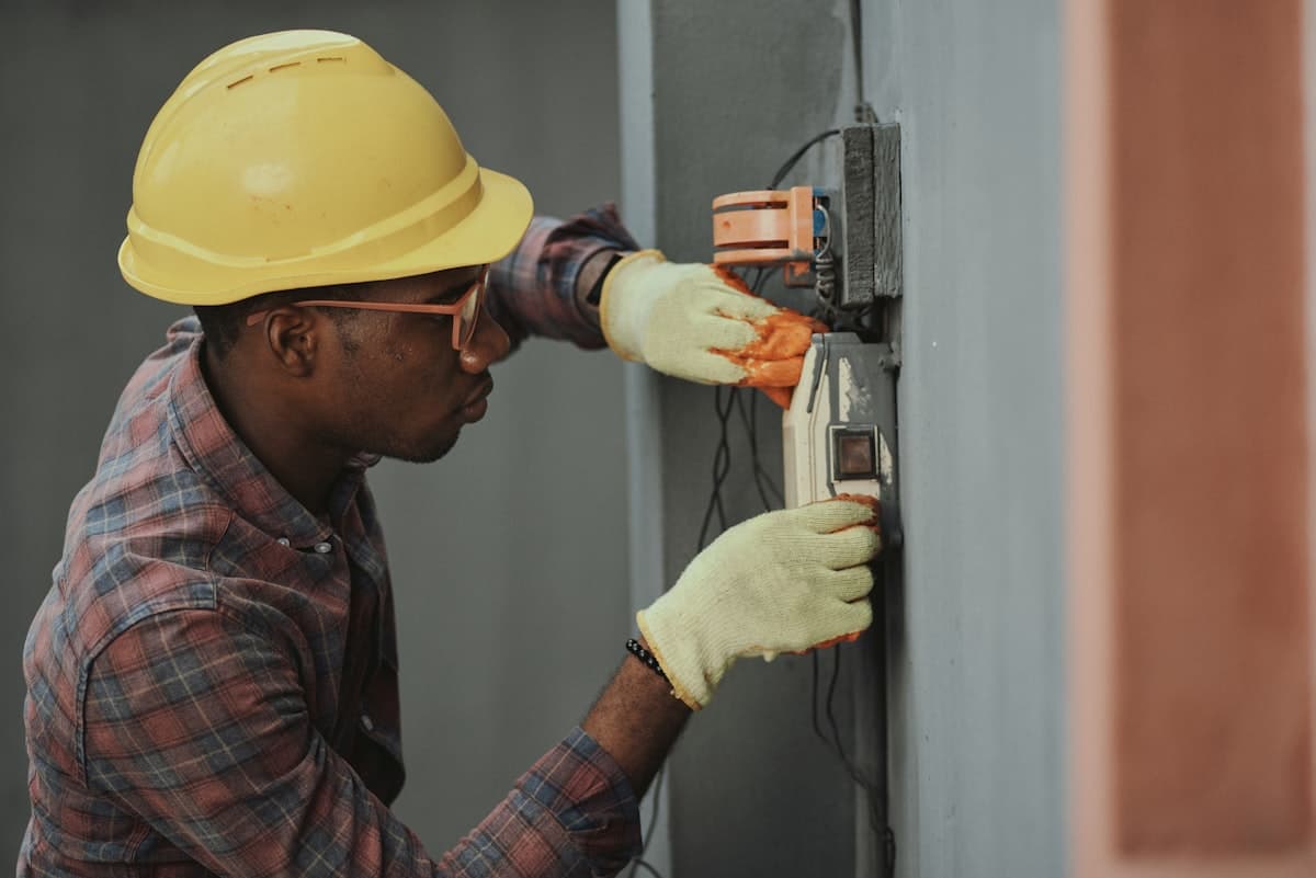 An electrician installing wiring into a wall-mounted junction box