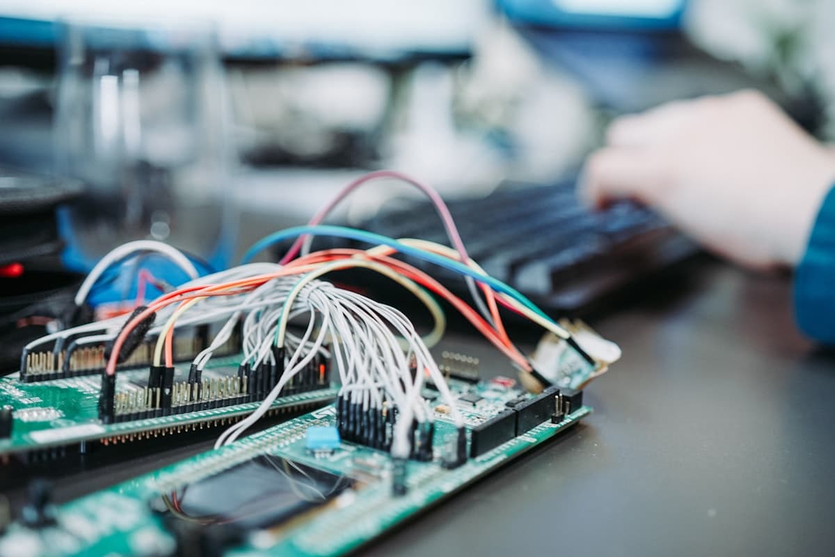 A close-up of a wired microcontroller board beside a hand typing on a keyboard