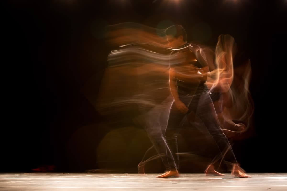 Long-exposure photo of dancers in motion, trailing light and movement