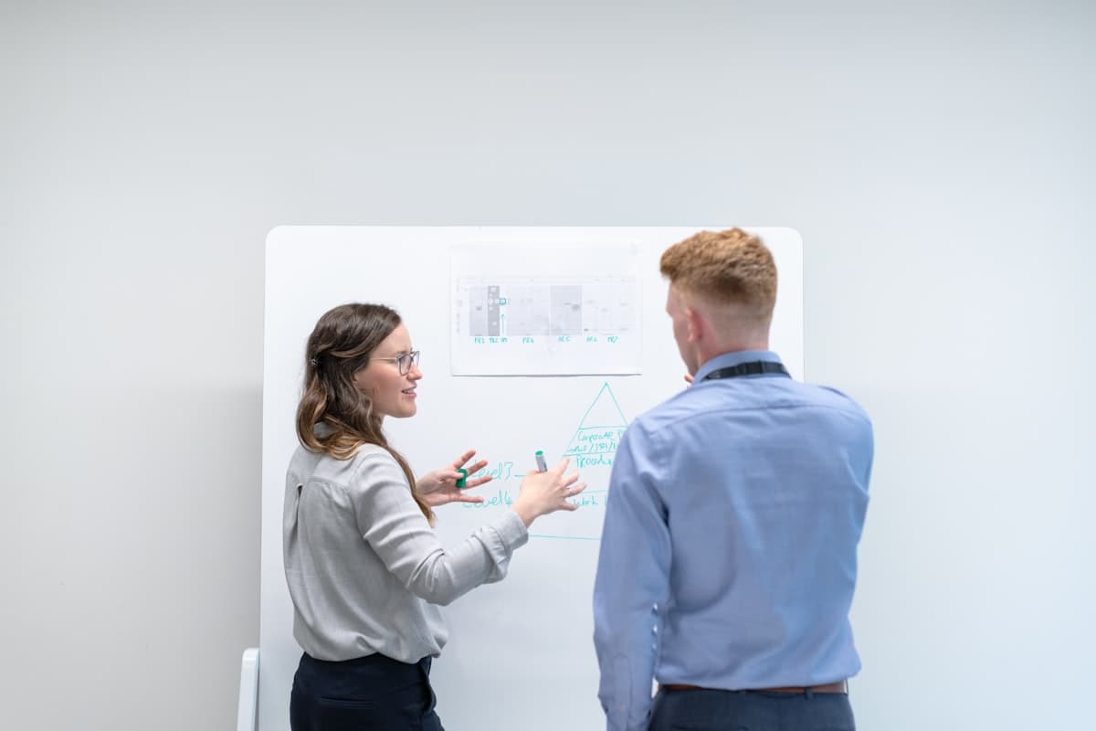 Two colleagues discussing a plan at a whiteboard