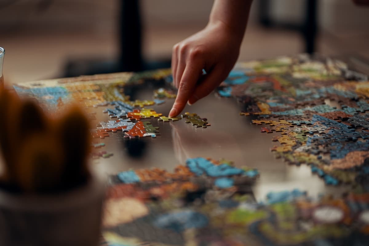 A hand placing a puzzle piece among other connected pieces
