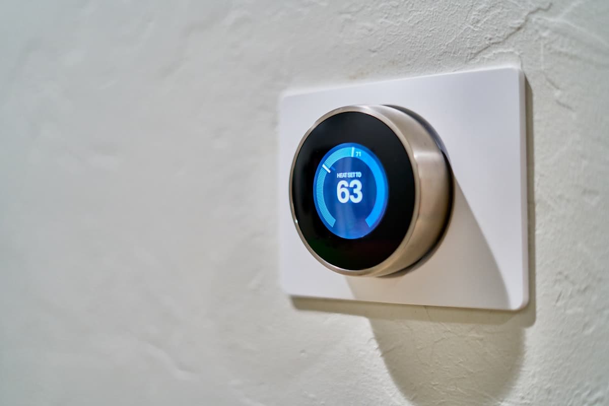 A smart thermostat mounted on a wall displaying its temperature setting