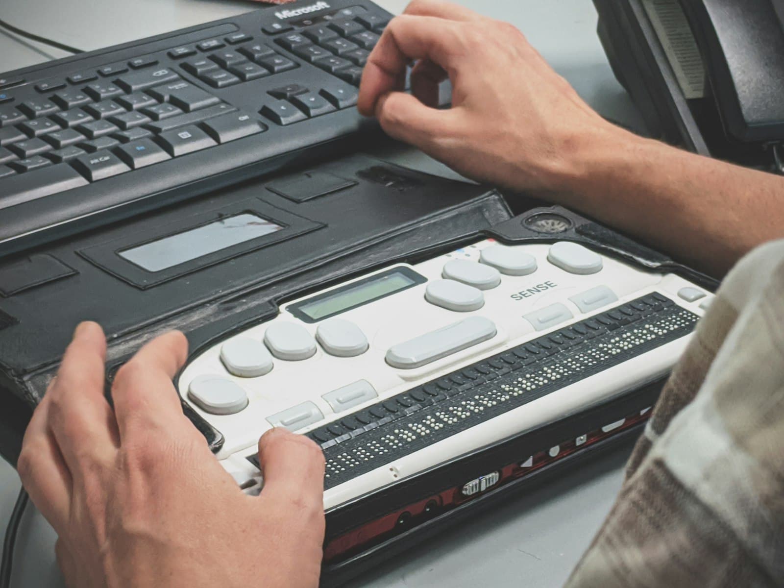 Hands operating a braille writer device