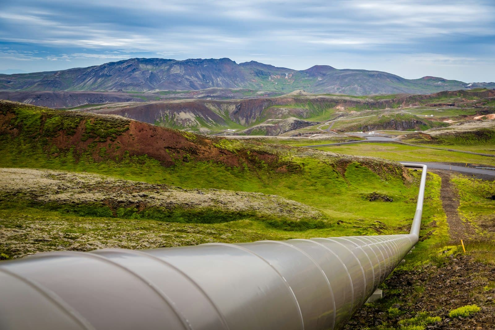 An industrial pipeline running through a green landscape