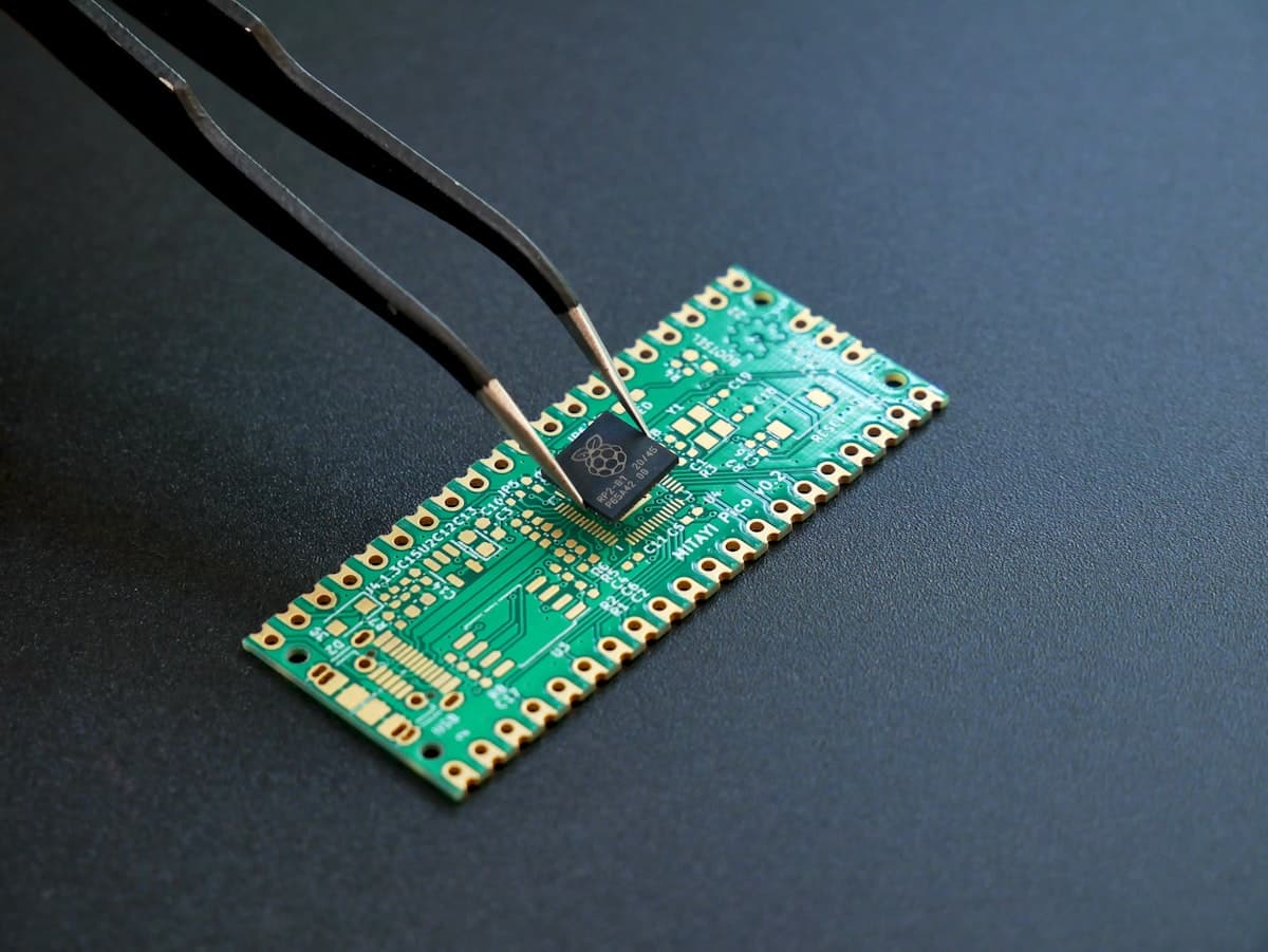 Tweezers placing a microchip onto a green circuit board